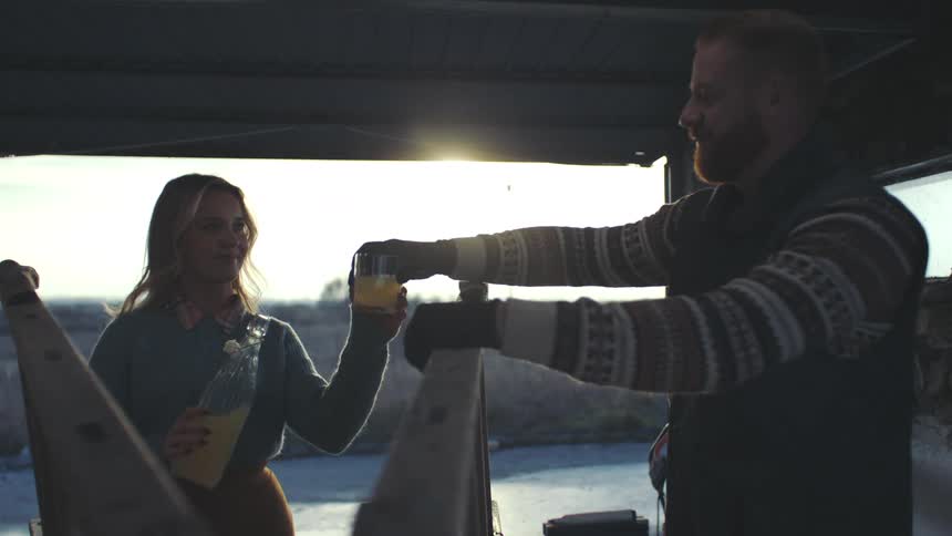 Man with a saw sawing a wooden staircase and a woman next to him pouring a glass of orange juice