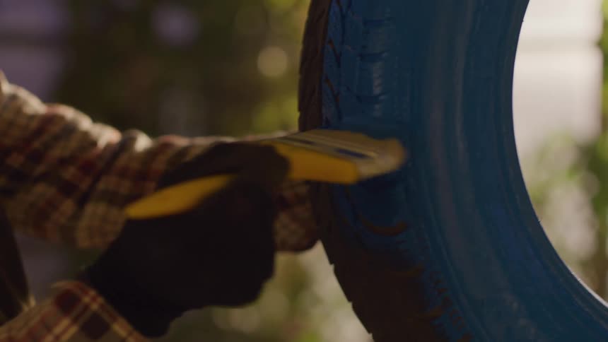 Man painting an old tire blue