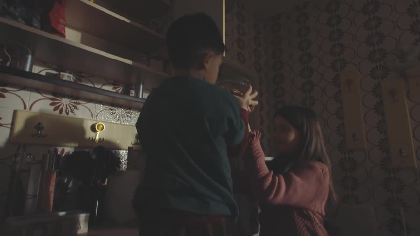 Boy and little girl picking up cookie jar from kitchen and walking around the room