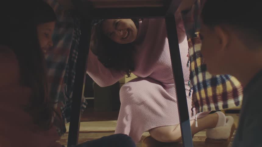 Smiling woman finding two children under a table with a hidden cookie jar