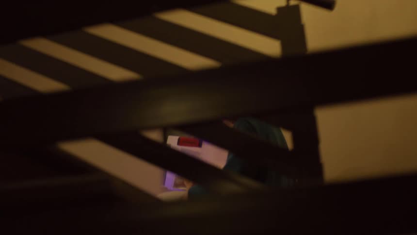 Boy walking down the stairs of a house carrying a pillow and a box with glowing lights