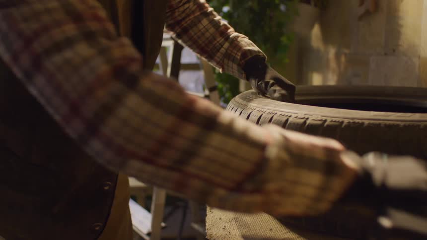 Man with a screwdriver drilling an old tire on a table