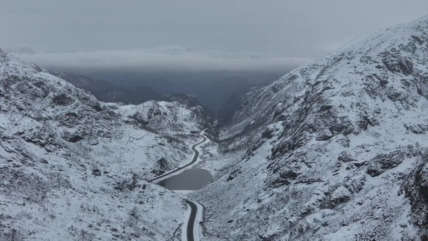 Aerial view of a river leading to an ocean surrounded by snowcapped mountains