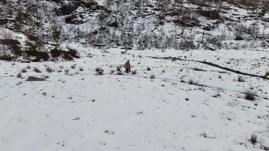 A man is walking towards the mountain in the snow