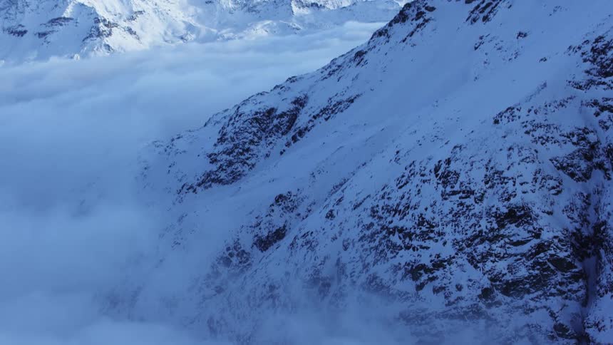 Low lying clouds fill the valley between snow covered mountains during a winter day