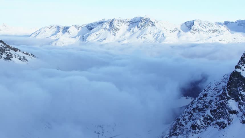 Fog fills the valley between snowy mountains on a winter day
