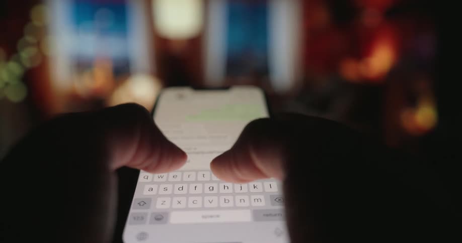 The fingers of a person who is holding a cell phone in their hands and typing messages to someone quickly