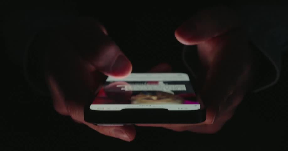 Hands holding a smartphone in dark environment