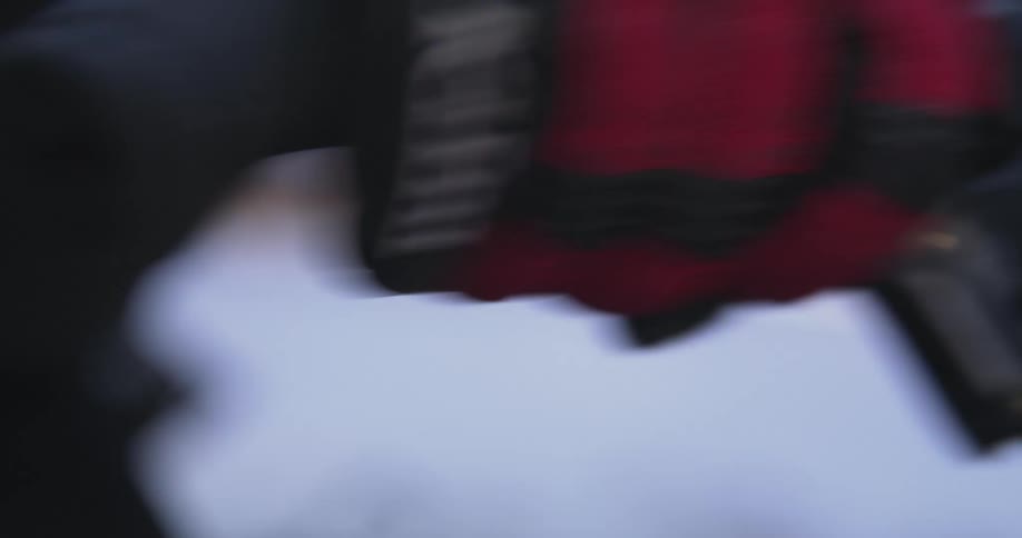 A closeup of a gloved hand gripping a handlebar with the glove featuring black and red padding