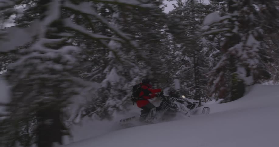 Person riding a snowmobile down a snowy mountain
