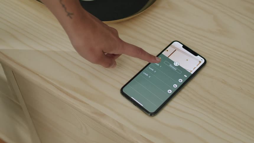 Finger clicking on a smartphone screen on a wooden surface