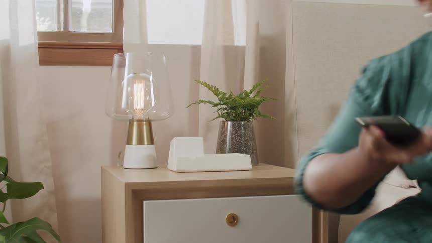 Woman closing a cabinet drawer and picking up her smartphone from a stand
