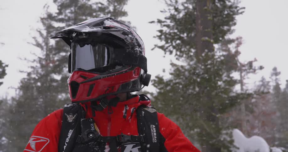 Person wearing winter gear for extreme snow sports with black and red helmet reflecting the surrounding environment