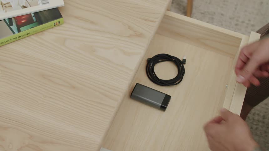 Barefoot man in a sweater removes a device from the drawer of the coffee table