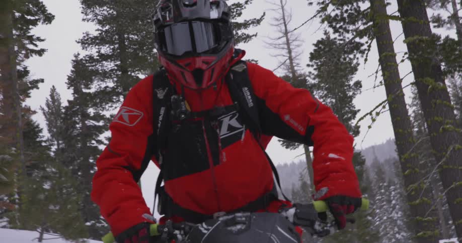 Person in helmet walking through snow with conifers