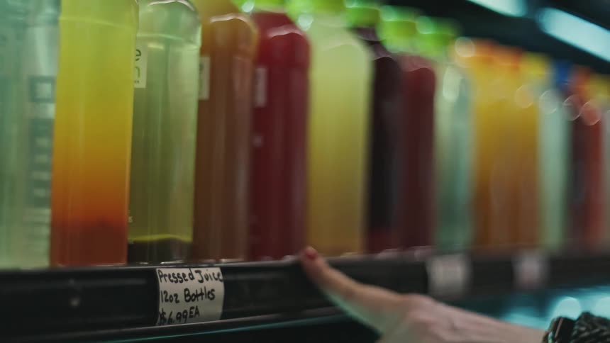 A customer chooses a bottle of juice in the store