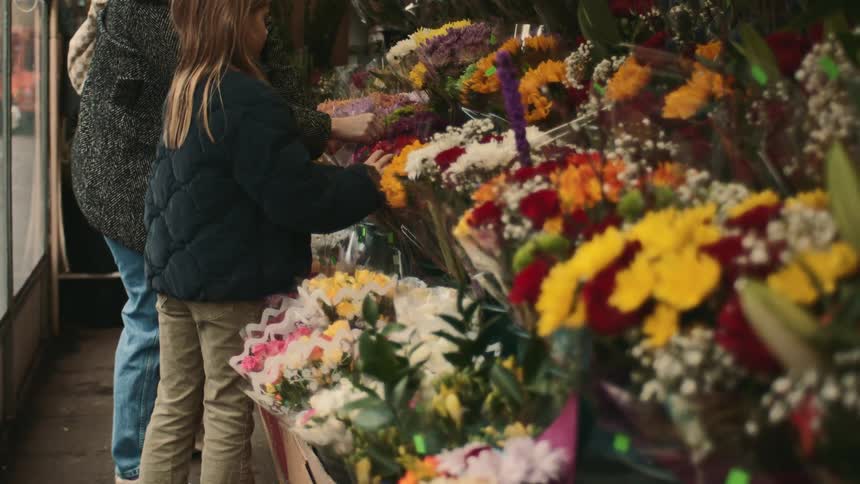 A mother and her daughter are shopping together for flower bouquets