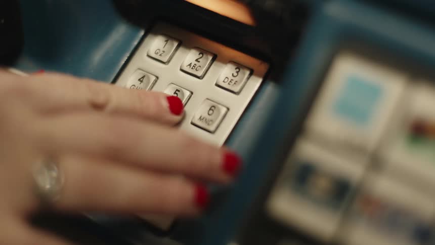 A persons hand with red painted nails clicking buttons with numbers on a machine