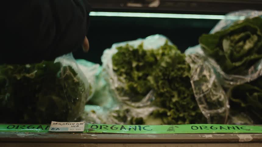 Hand picking up a bag of lettuce