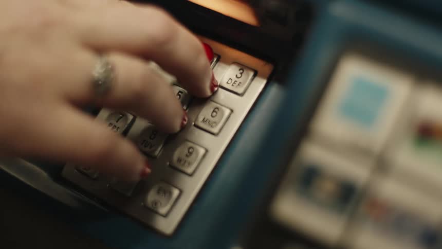 A persons hand with red nails typing on some numbered buttons