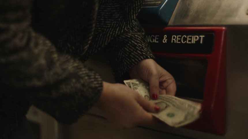Pair of womans hands withdrawing money from an atm