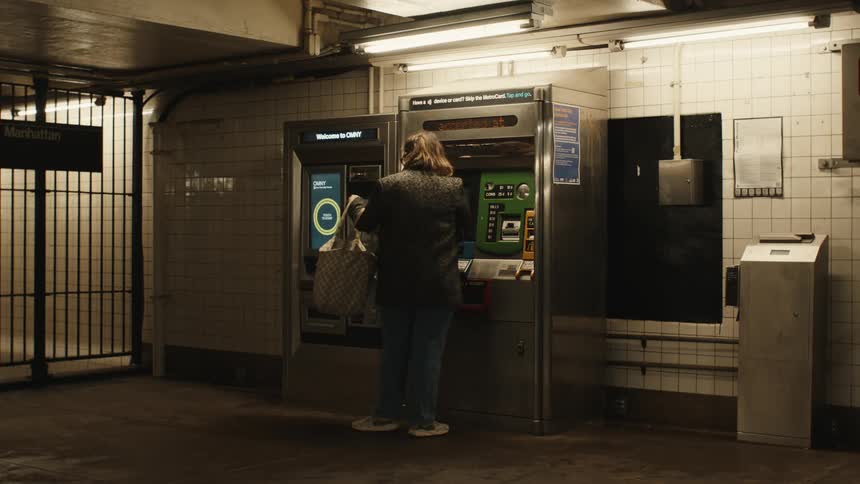 A woman walks up to the kiosk to buy a metro pass