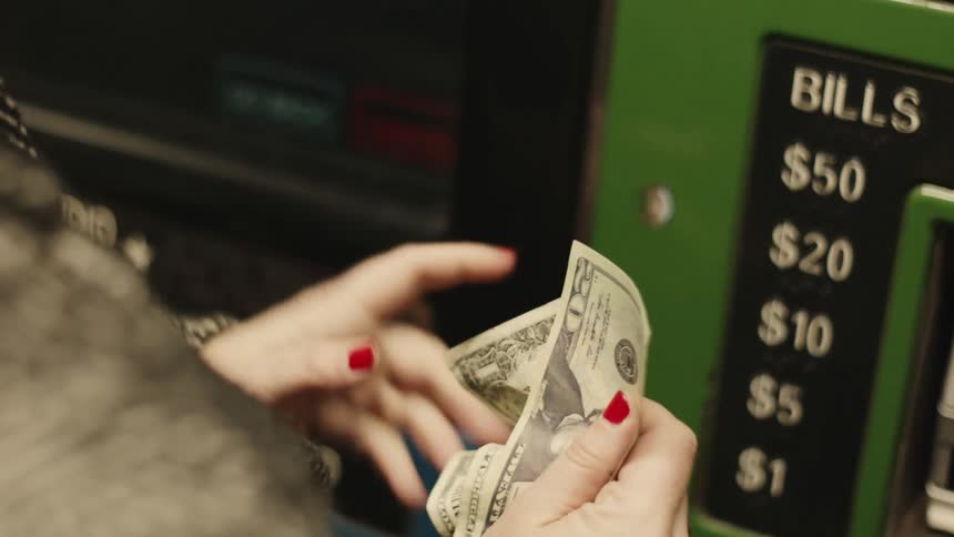 Hand depositing money into an atm