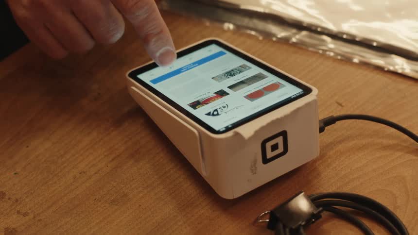 A person is pressing the screen on the payment processor