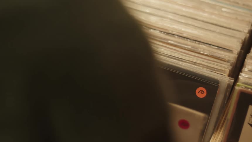 A person is browsing through a collection of vinyl records with colorful price stickers