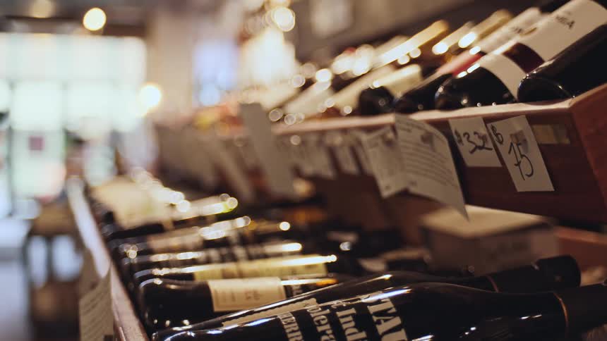 Woman reads the details provided about different products while shopping for wine during the daytime