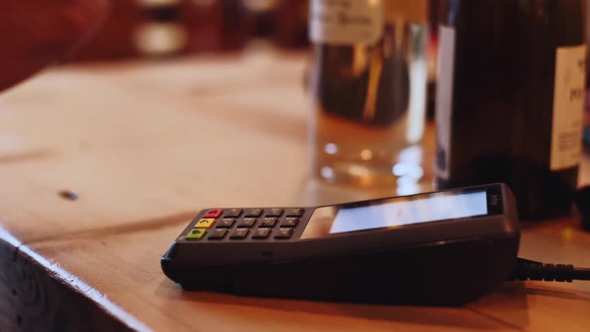 Hand swiping a contactless card on a payment machine