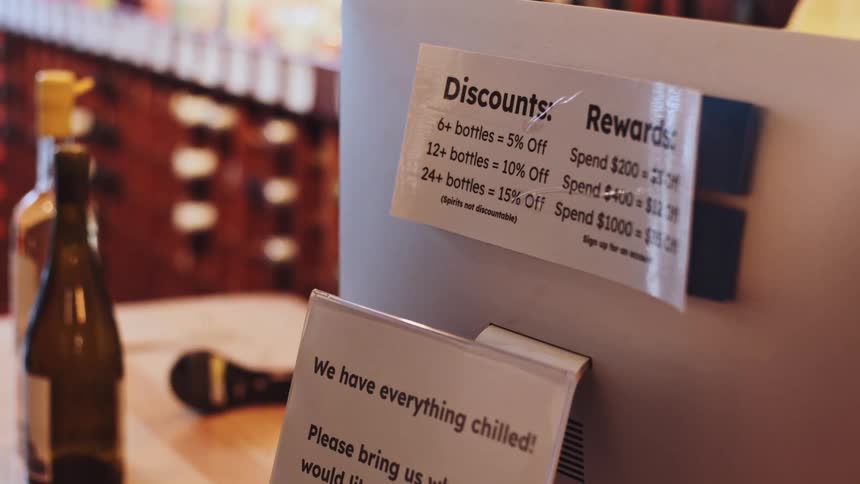 Computer monitor displays posters with information about discounts and rewards at a liquor store