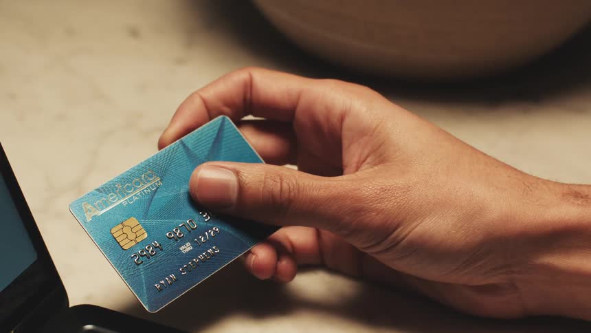 Hand holding a blue card near an electronic device