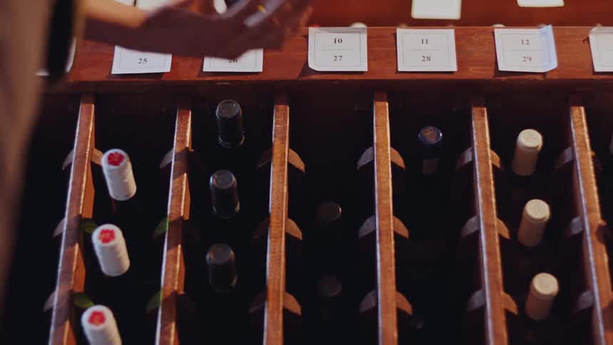 Woman browses through the products on a wooden rack while shopping for wine