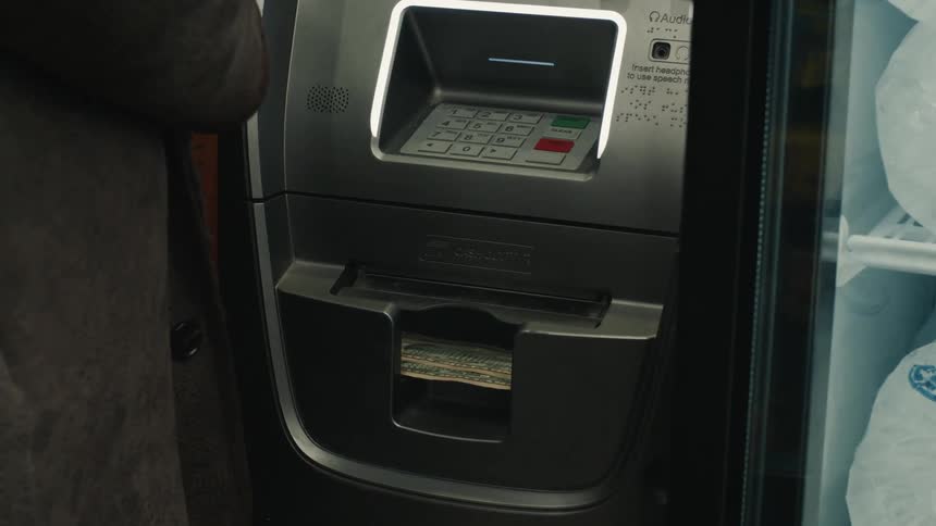 An automatic teller machine with money coming out of it and some people walking in front of it