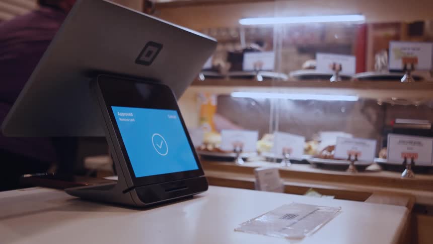 A person is making a payment using a card on a tabletbased pointofsale system