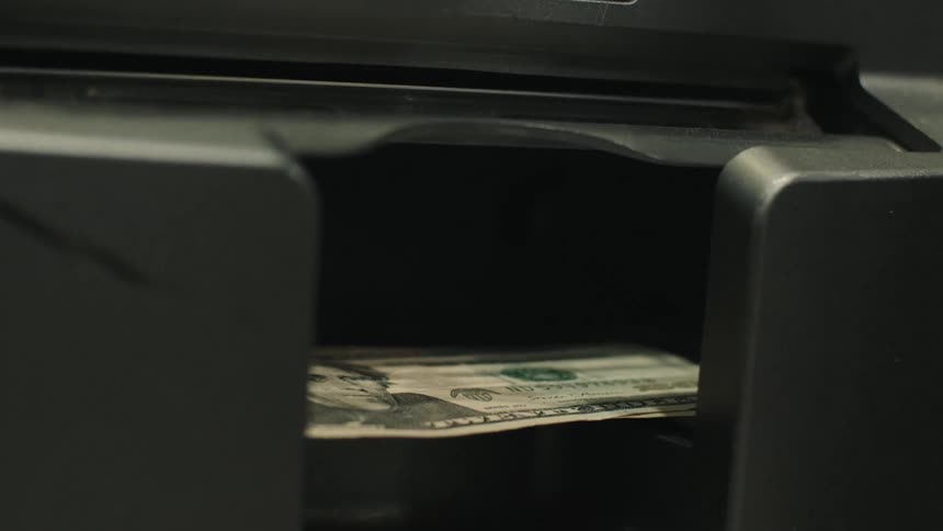 Hand taking cash notes from an atm