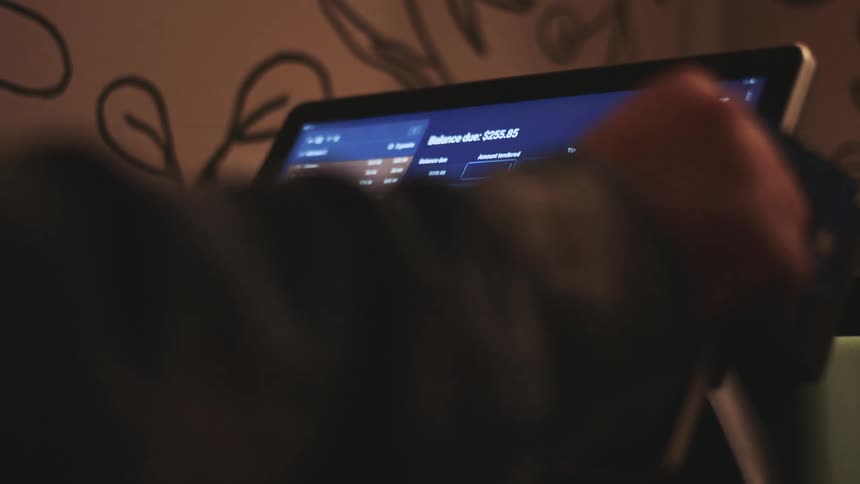 Hand interacting with a touchscreen device displaying a management system interface