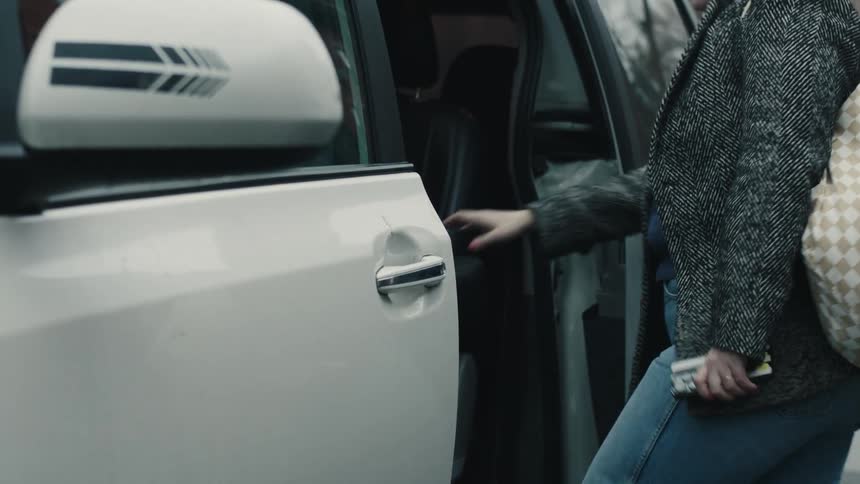 A woman gets in the backseat of the car