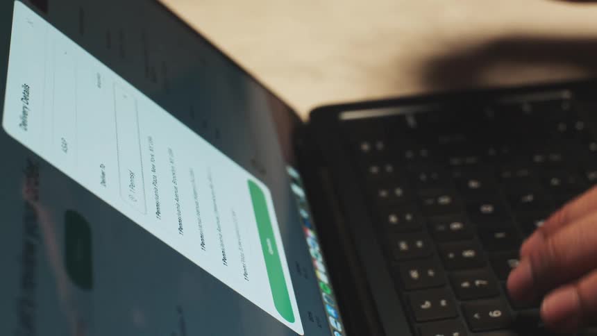 Laptop screen displaying an online payment form while a hand types on the keyboard