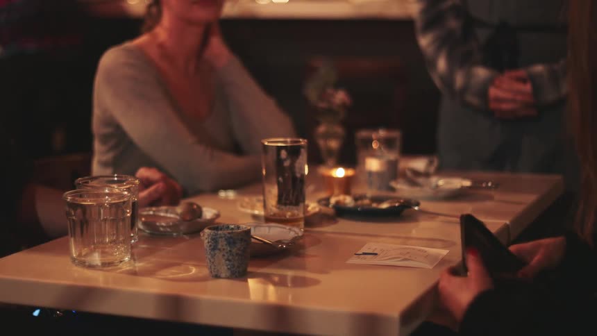 Woman in a restaurant handing over a card to pay the bill