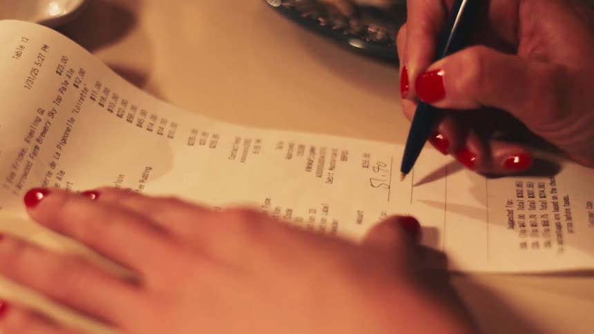A woman signs a receipt to pay