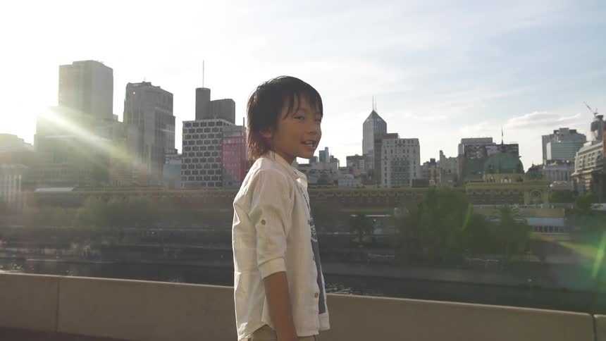 A child stands in front of city buildings