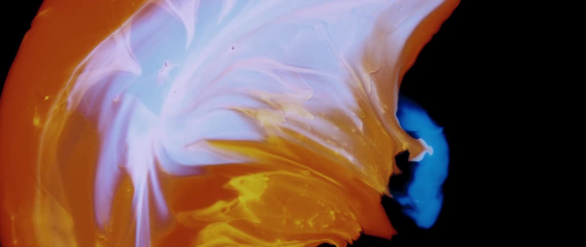 Extreme close up of colorful paint expanding on a black background
