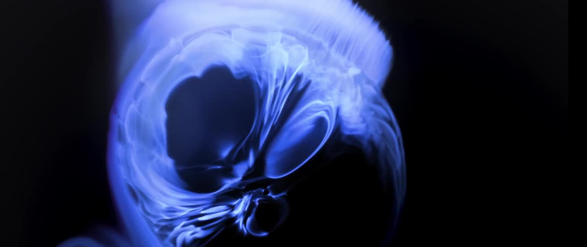 Abstract blue paint expanding against a black background