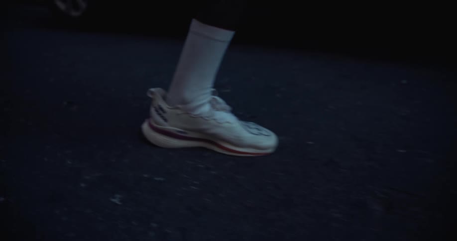 Feet of a person with white sneakers running on the street
