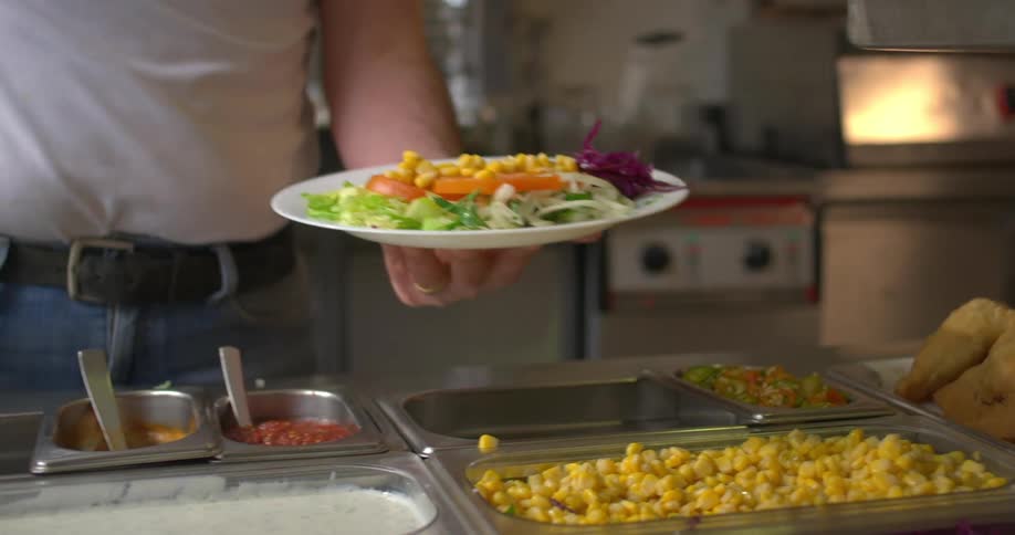 A man serves a salad with dressing in the restaurant