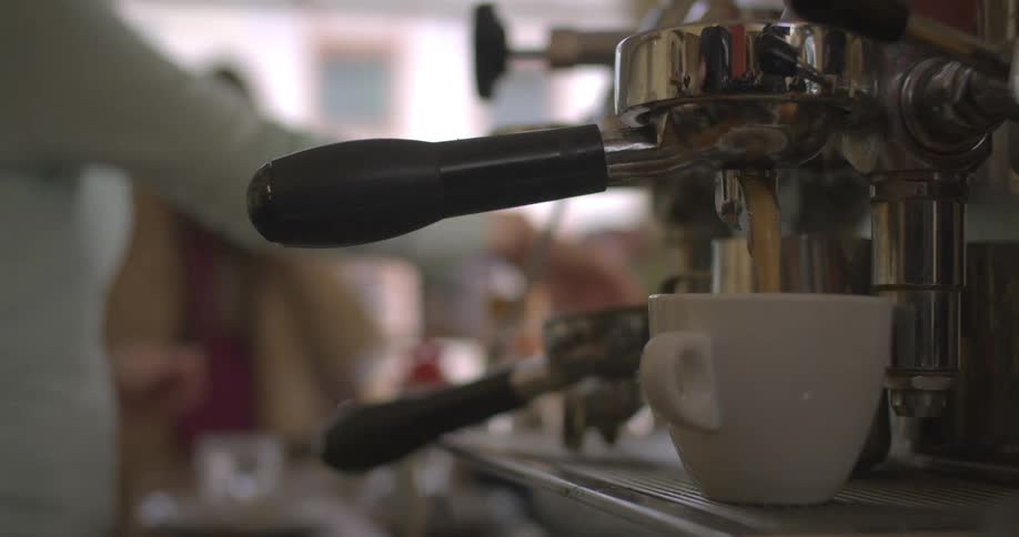 Pair of hands producing a cappuccino in a machine