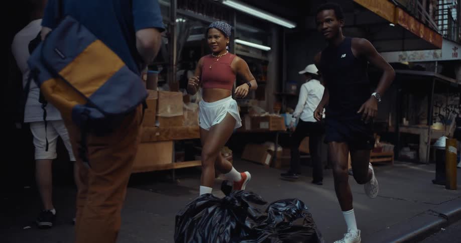 Two people are jogging on a city street near a market area