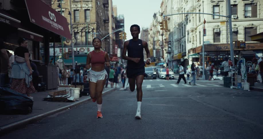 Man and woman running down an urban city street with pedestrians